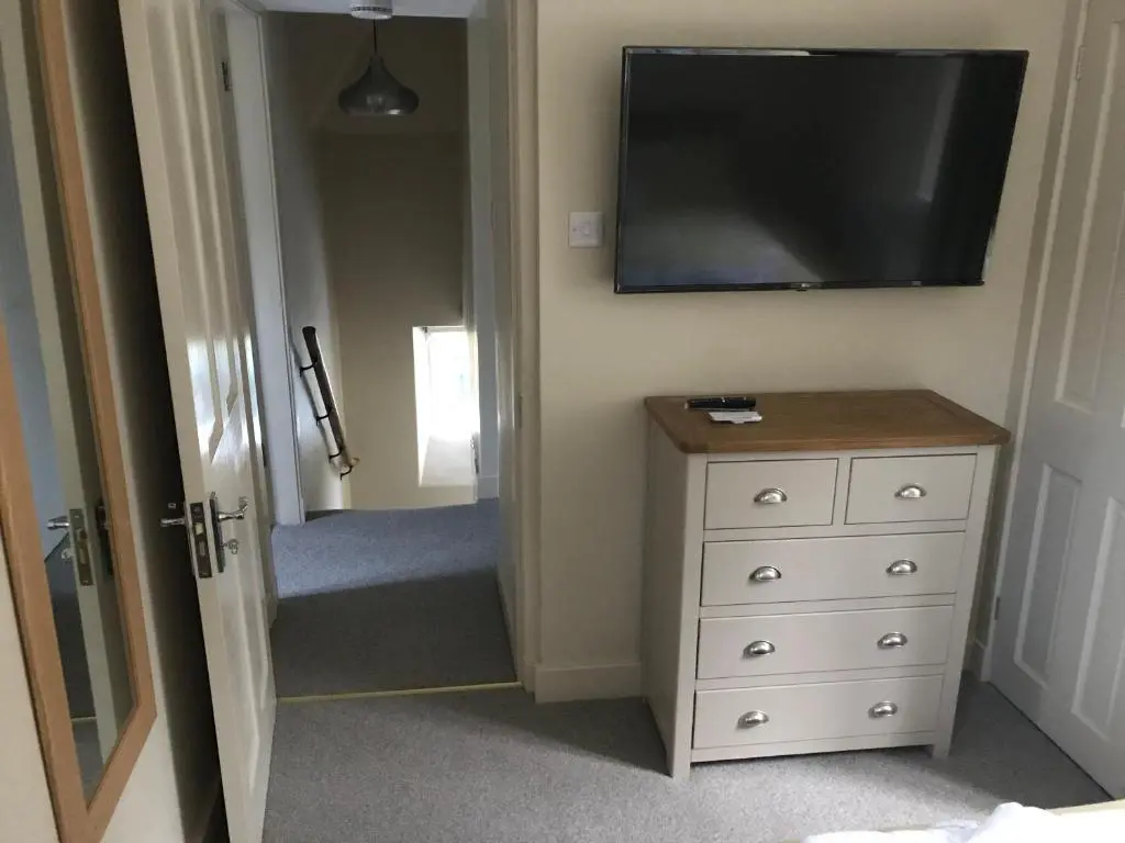a bedroom with a dresser and a flat screen tv at North Lodge in Invergarry