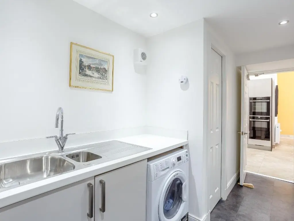 a kitchen with a sink and a washing machine at Skene House Court in Dunecht
