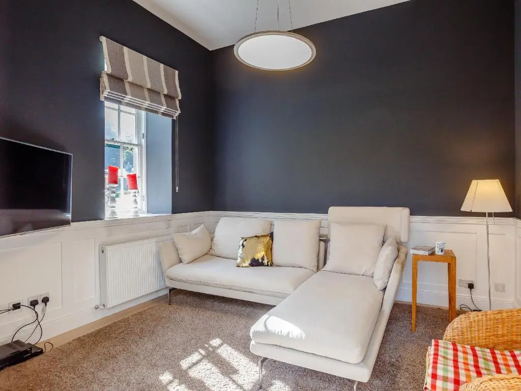 a living room with a white couch and a tv at Skene House Court in Dunecht