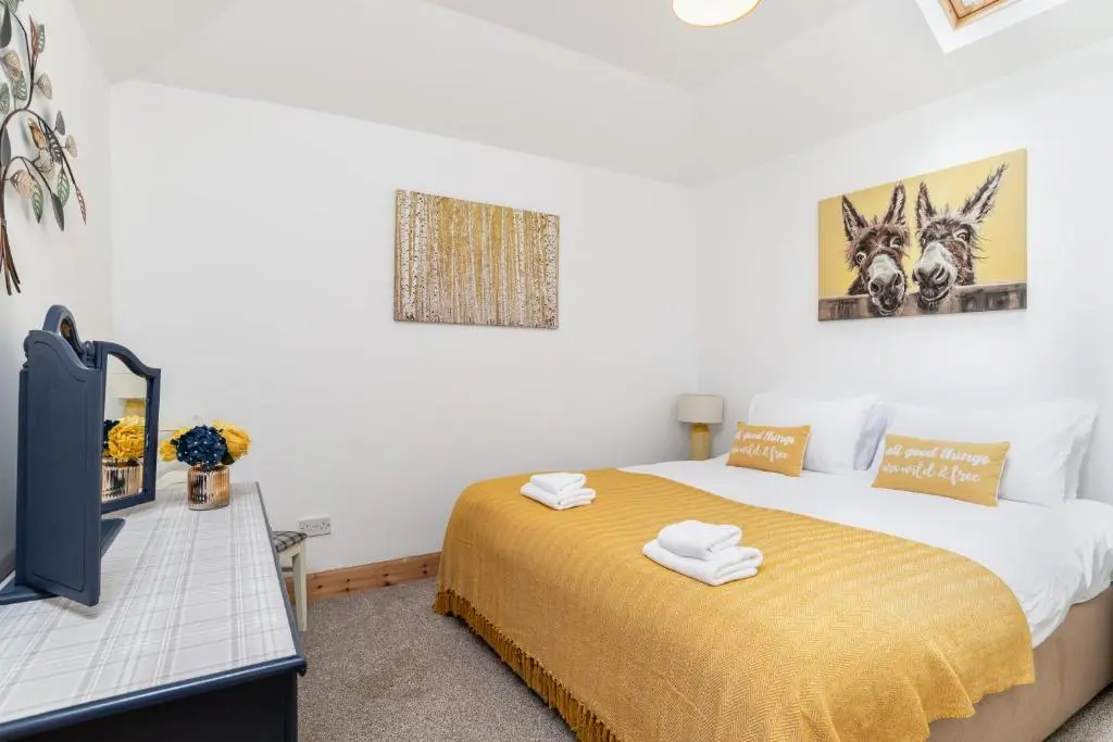 a bedroom with a bed with a yellow blanket at Dormie Cottage, lovely bright and spacious bungalow with wood fire in Ballater