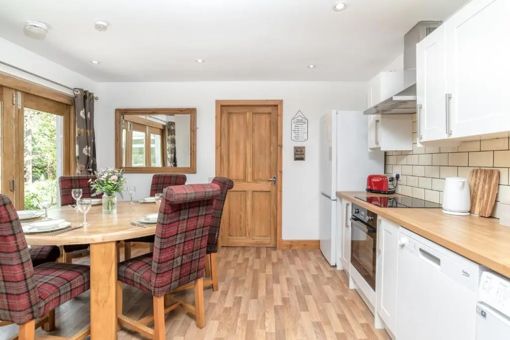 a kitchen and dining room with a wooden table and chairs at Dormie Cottage, lovely bright and spacious bungalow with wood fire in Ballater