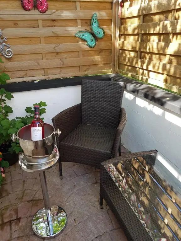 a patio with a chair and a table and butterflies at The little garden hoose in Inverness