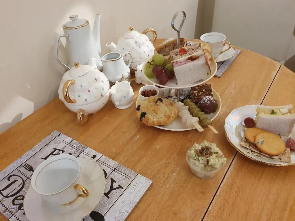 a wooden table with plates of food and teapots at The little garden hoose in Inverness