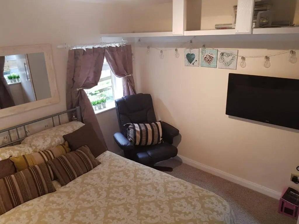 a bedroom with a bed and a chair and a television at The little garden hoose in Inverness