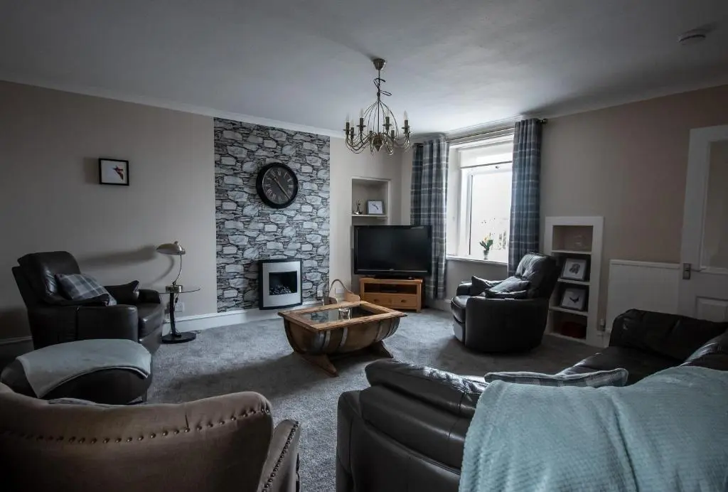 a living room with couches and a stone fireplace at The View 3-Bed Cottage Findochty Buckie Moray in Findochty