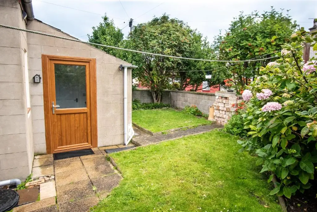 a house with a wooden door in a yard at The View 3-Bed Cottage Findochty Buckie Moray in Findochty