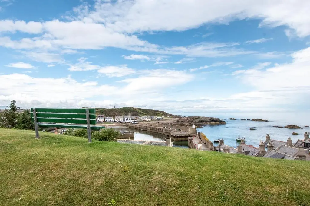 a bench sitting on a hill overlooking a body of water at The View 3-Bed Cottage Findochty Buckie Moray in Findochty