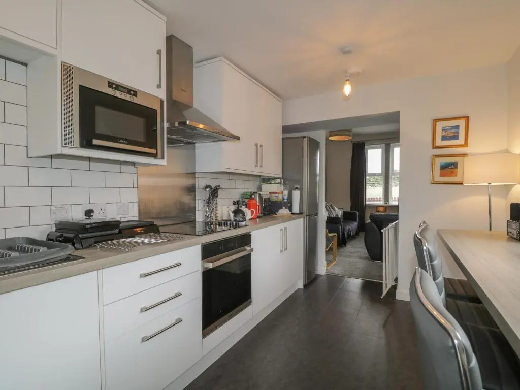 a kitchen with white cabinets and a stove top oven at Blantyre Cottage in Muir of Ord