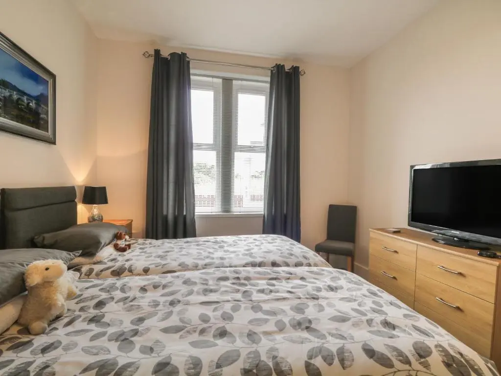 a teddy bear sitting on a bed in a bedroom at Blantyre Cottage in Muir of Ord