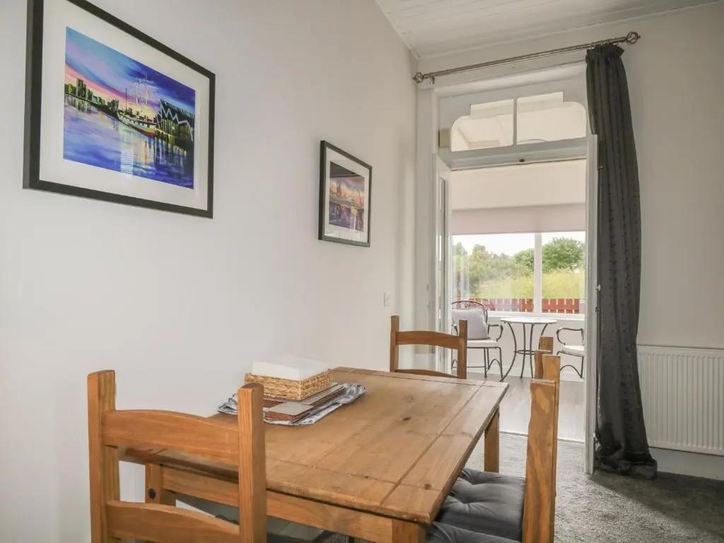 a dining room with a wooden table and chairs at Blantyre Cottage in Muir of Ord