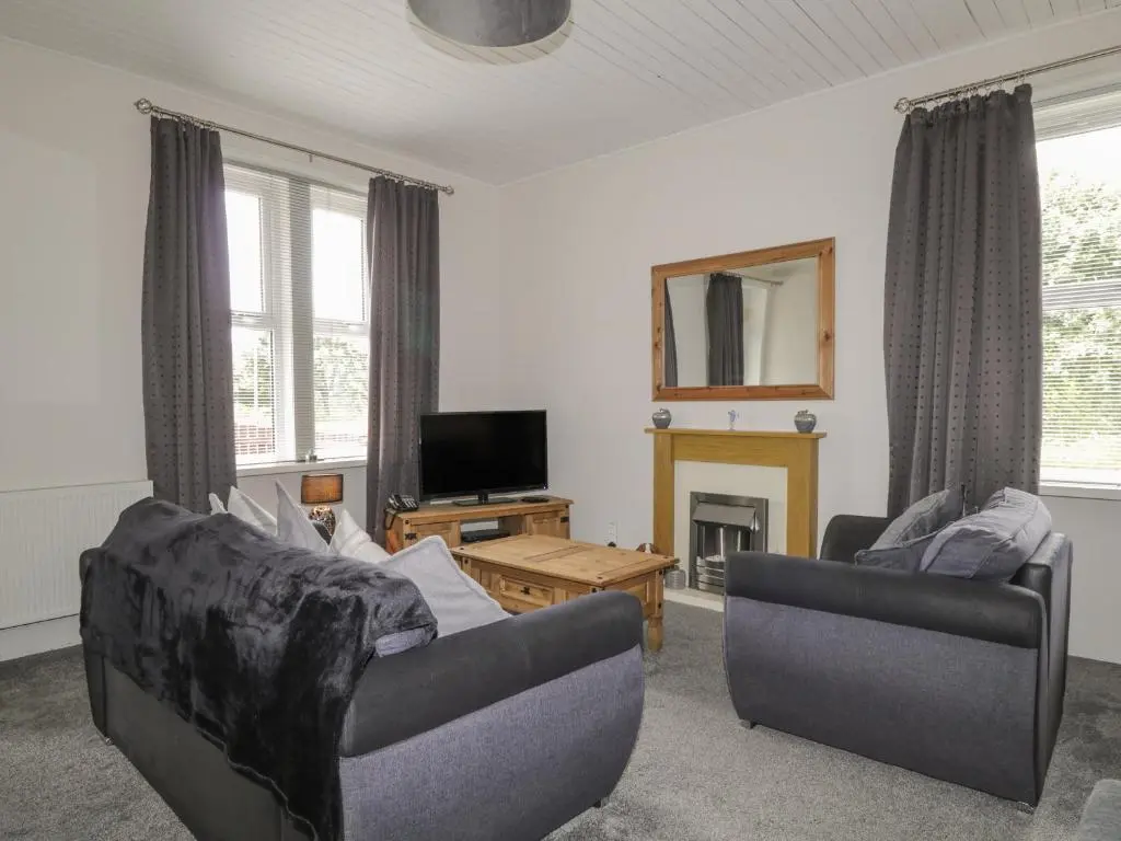 a living room with two couches and a tv at Blantyre Cottage in Muir of Ord