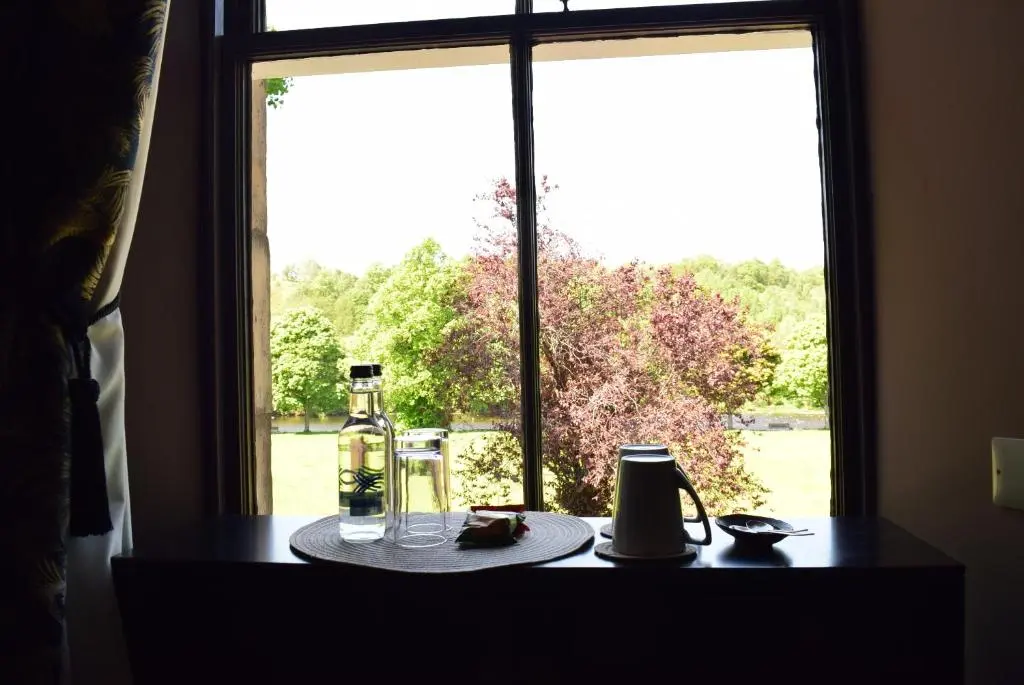 a table with a bottle and glasses on a window at The Mash Tun in Aberlour