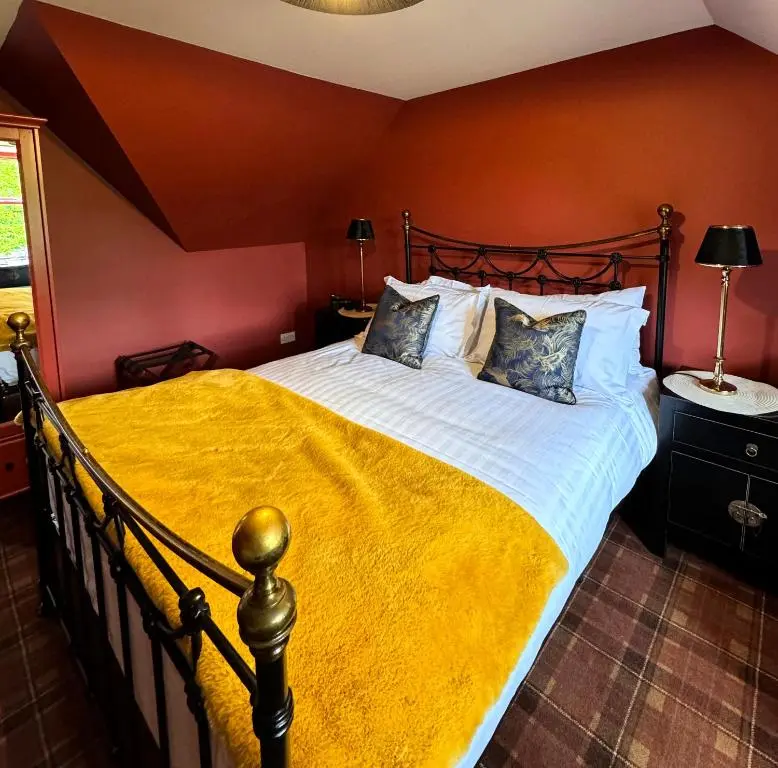 a bedroom with a large bed with a yellow blanket at The Mash Tun in Aberlour