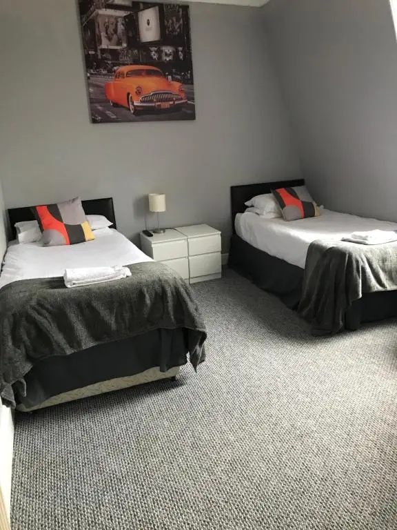 a bedroom with two beds and a picture of a car on the wall at The Banks Of Ury in Inverurie