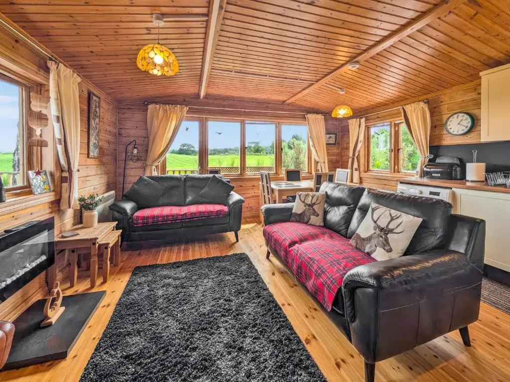 a living room with leather furniture and a wooden ceiling at Red Kite Cottage in Tore