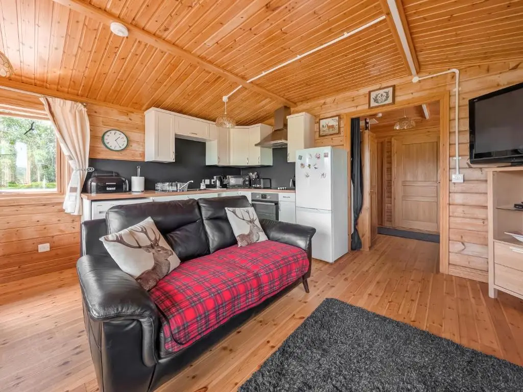 a living room with a couch and a kitchen at Red Kite Cottage in Tore