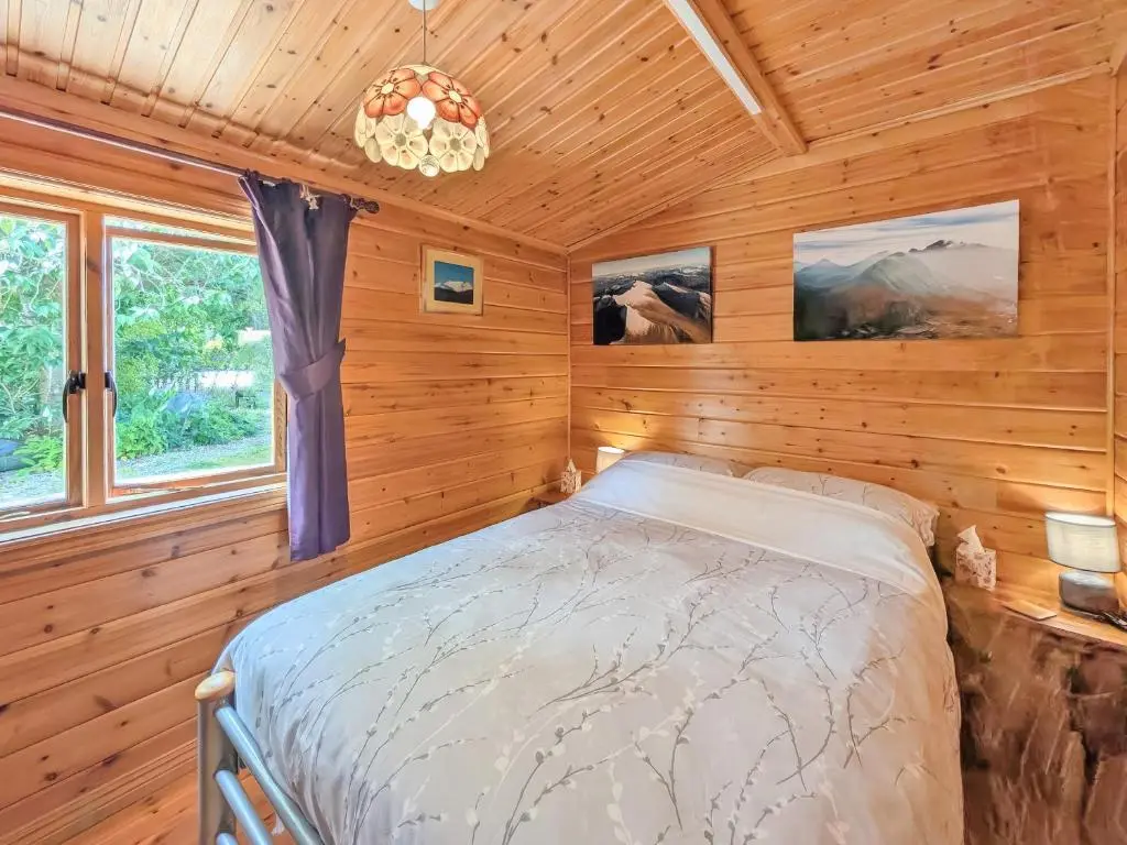 a bedroom with a bed in a wooden room at Red Kite Cottage in Tore