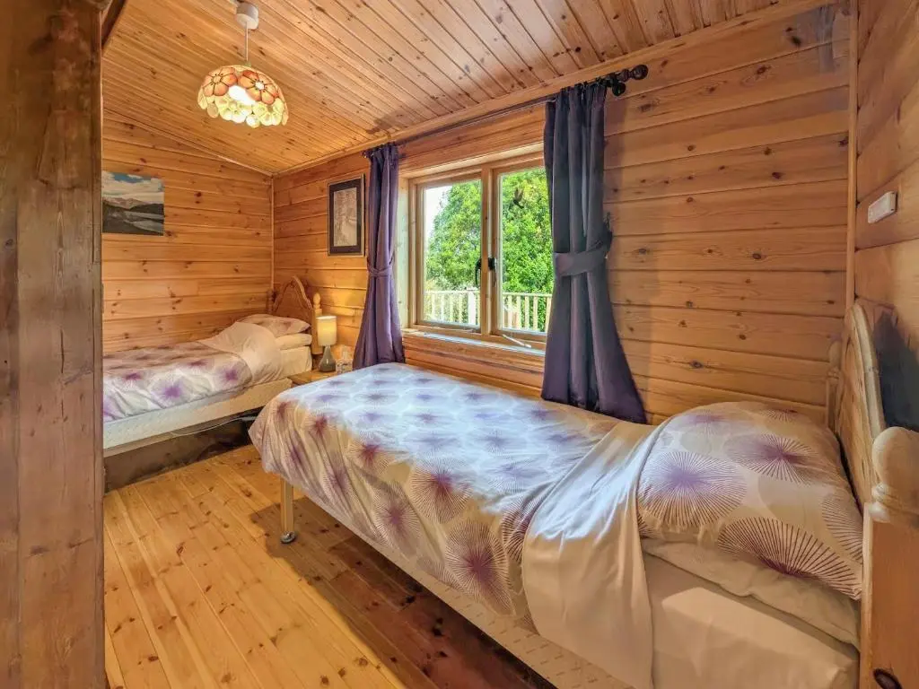 a bedroom with two beds in a log cabin at Red Kite Cottage in Tore