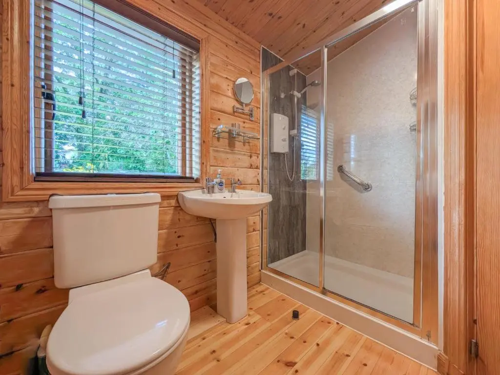 a bathroom with a toilet and a shower and a sink at Red Kite Cottage in Tore