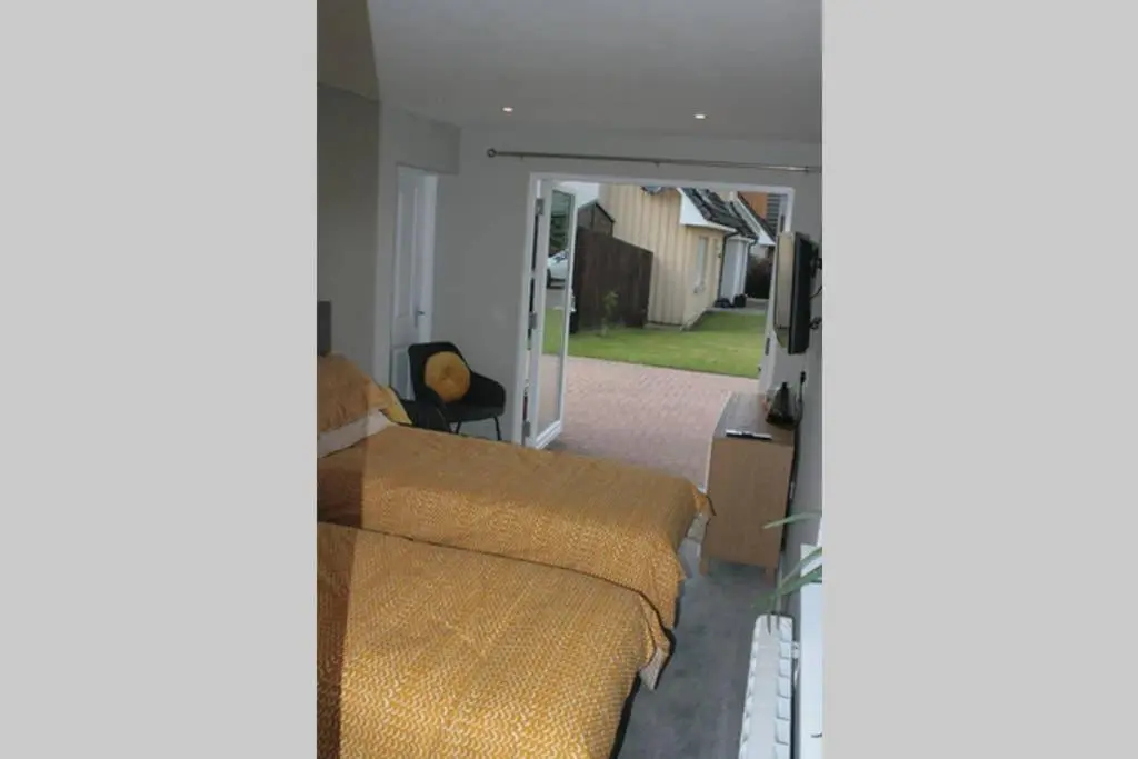 a bedroom with two beds and a door to a yard at The Snug at the Ski Lodge, Aviemore in Aviemore