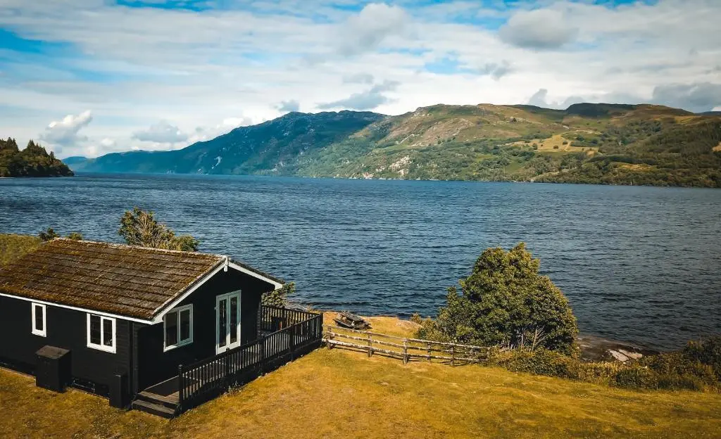 a small house next to a large body of water at Cabins at Old Pier House in Fort Augustus