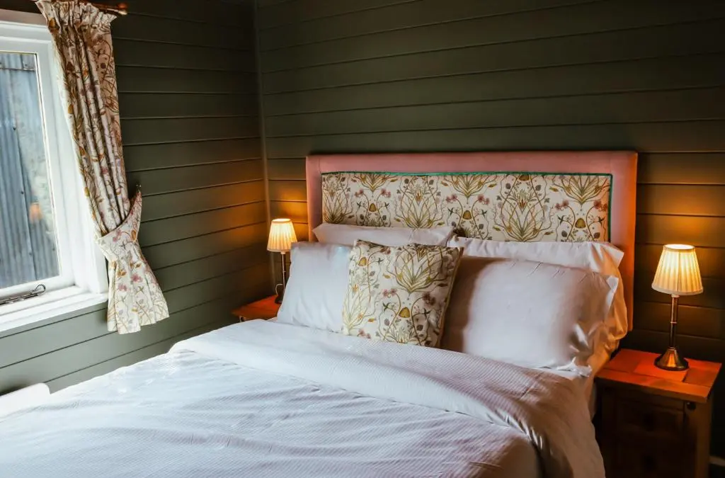 a bedroom with a bed and two lamps and a window at Cabins at Old Pier House in Fort Augustus
