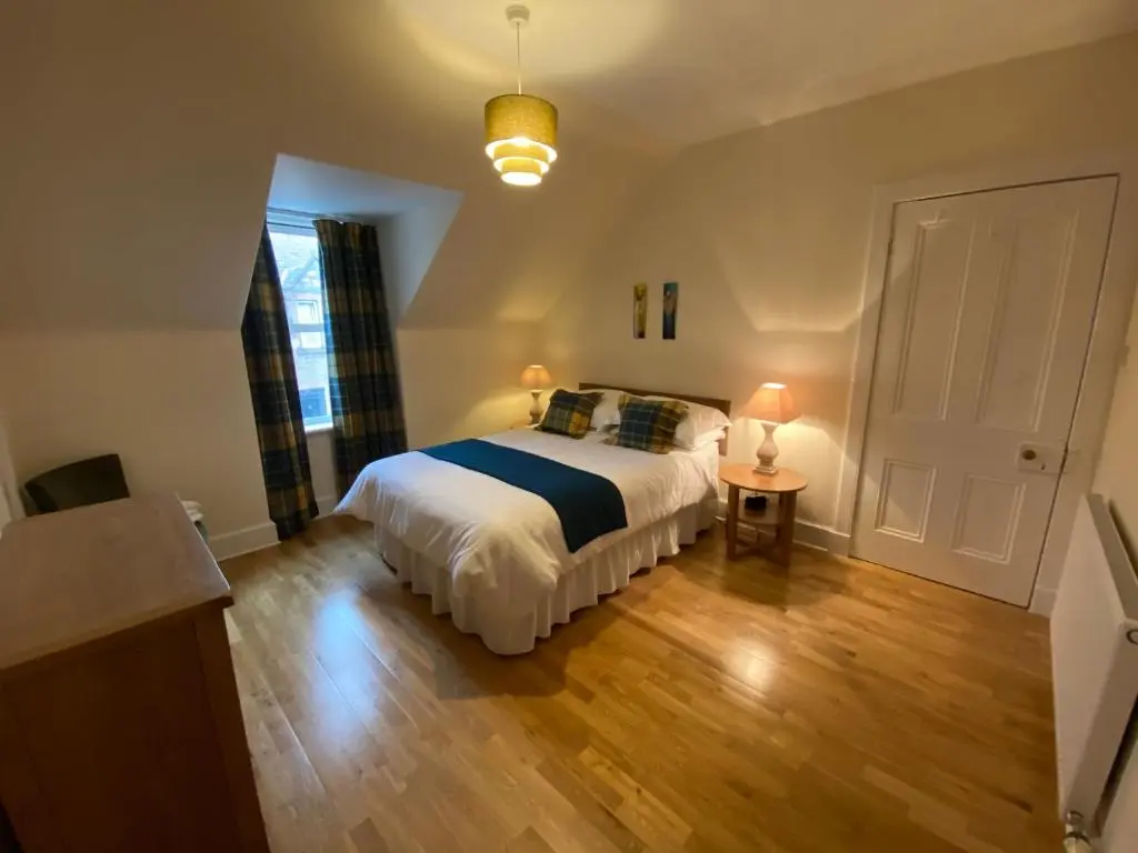 a bedroom with a bed and a table with two lamps at No. 20 in Inverness