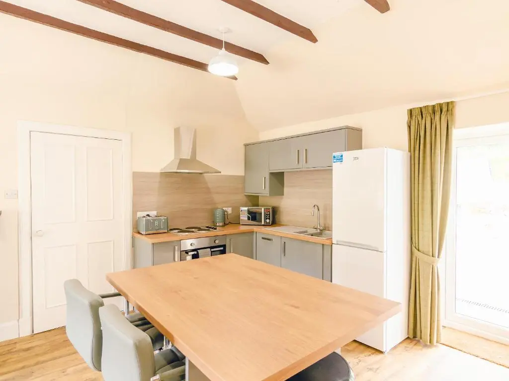 a kitchen with a wooden table and a white refrigerator at Keepers Cottage - Uk30246 in Cray