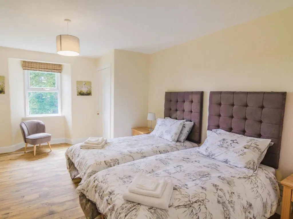 a bedroom with two beds and a chair at Keepers Cottage - Uk30246 in Cray