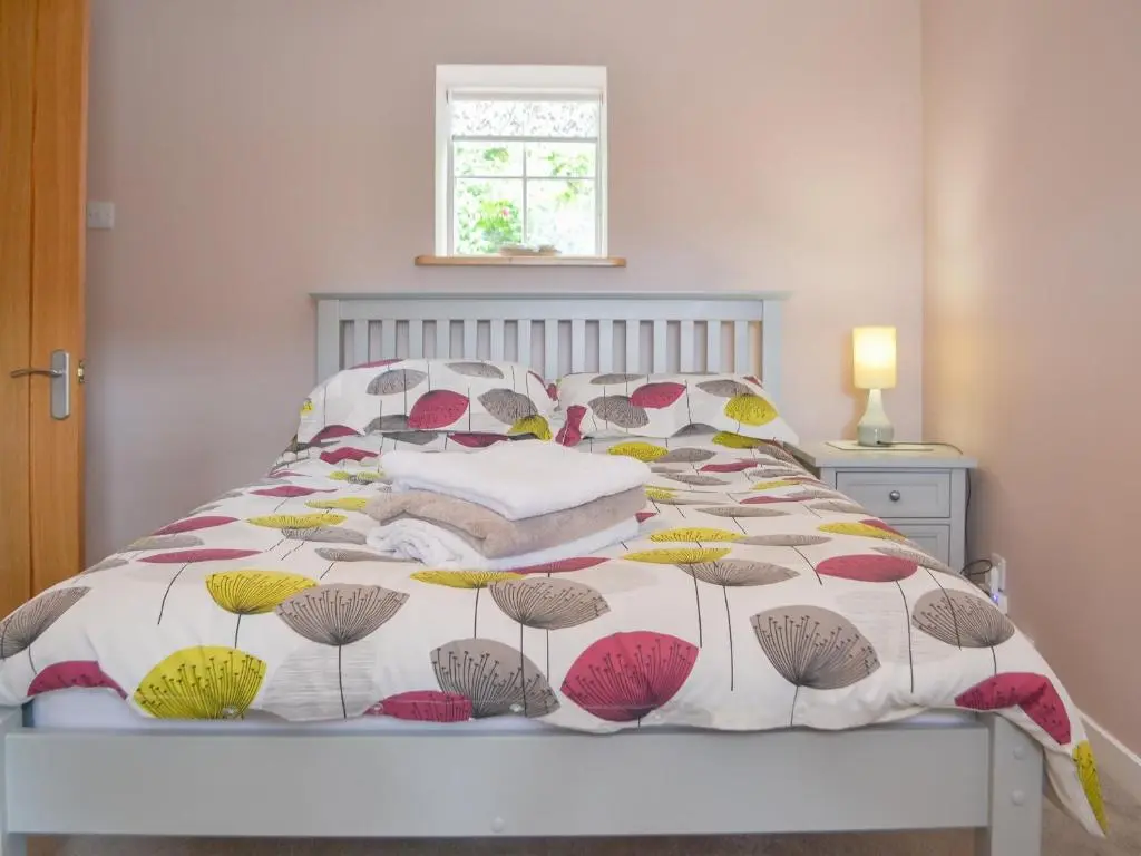 a bed with a colorful comforter and pillows on it at Mansefield Cottage in Boyndie