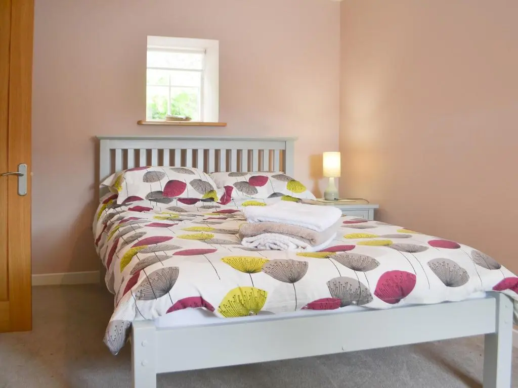 a bedroom with a bed with a colorful bedspread at Mansefield Cottage in Boyndie