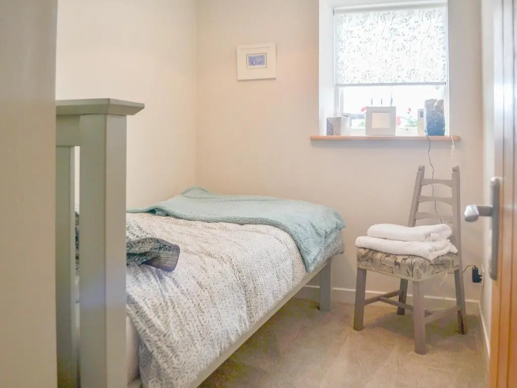a small bedroom with a bed and a chair at Mansefield Cottage in Boyndie
