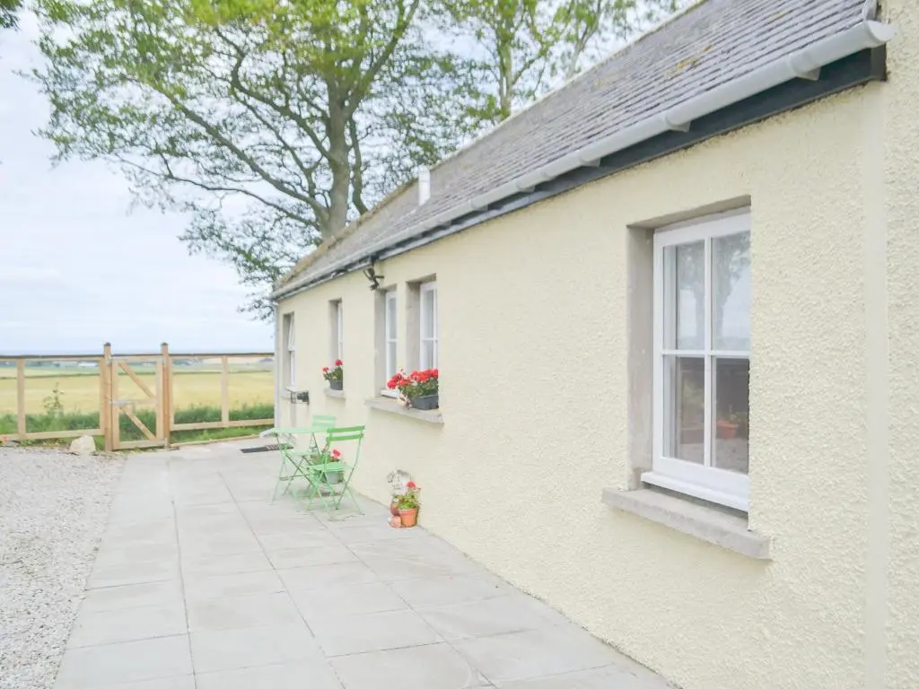 a yellow house with a patio and a window at Mansefield Cottage in Boyndie