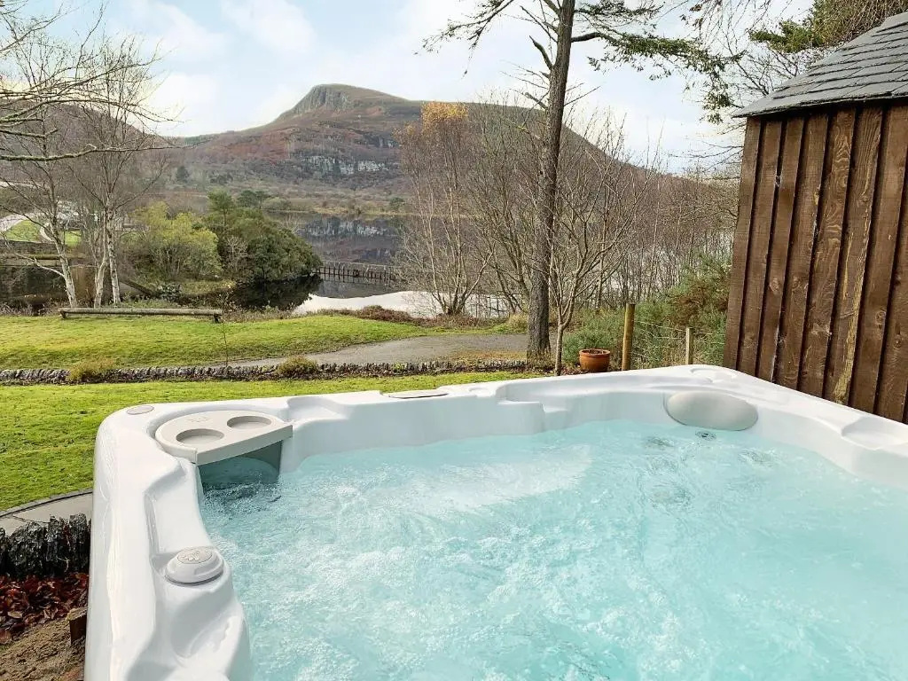 a hot tub in a backyard with a view of a mountain at Sluice Keeper's Cottage in Skelbo
