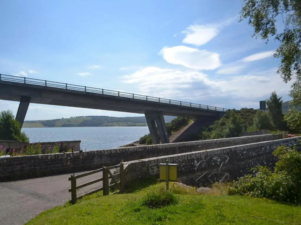 a bridge over a body of water next to a road at Sluice Keeper's Cottage in Skelbo