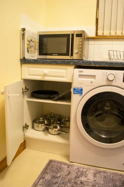 a kitchen with a microwave and a washing machine at Superb 2 Bedroom Flat - Refurbished Dec 2024 in Inverness