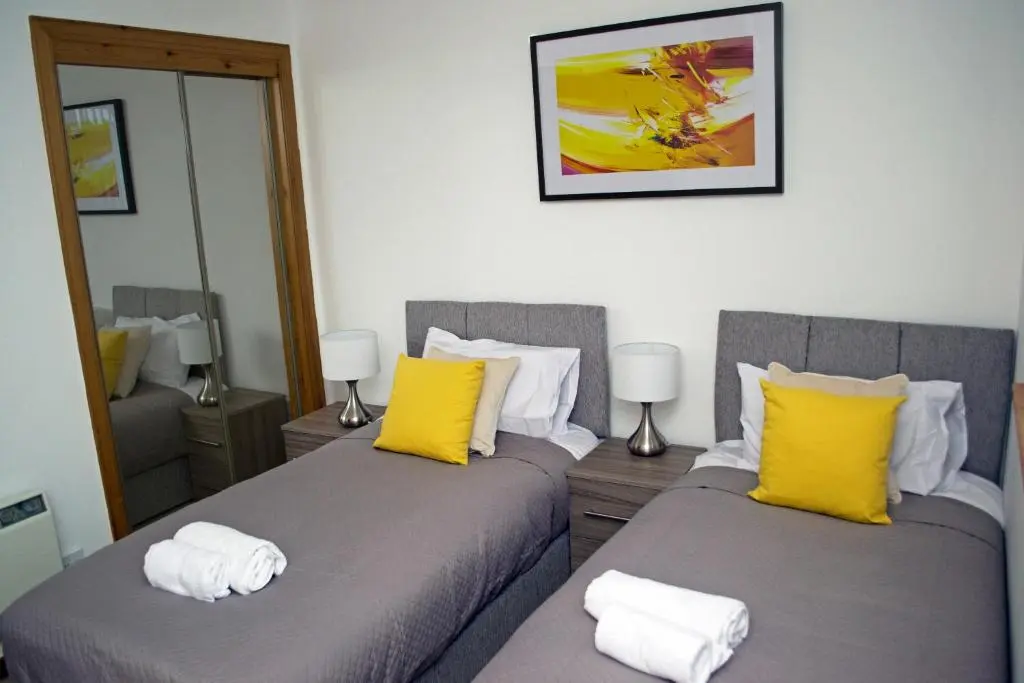 a bedroom with two beds with yellow and white pillows at Superb 2 Bedroom Flat - Refurbished Dec 2024 in Inverness