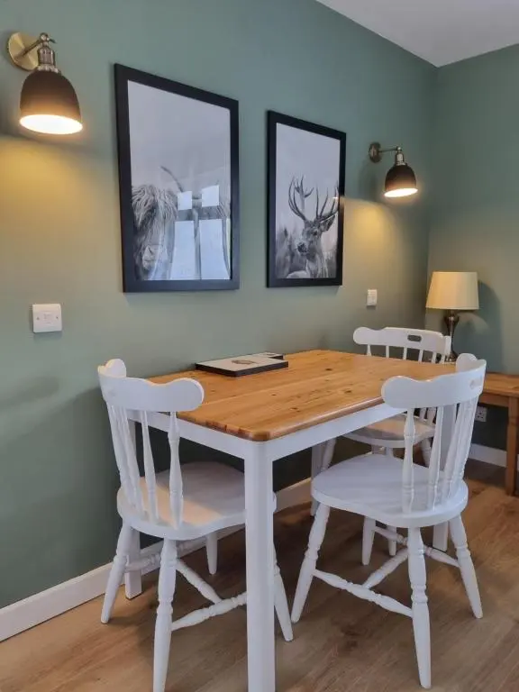 a dining room with a wooden table and white chairs at The Apartment at Old Pier House in Fort Augustus