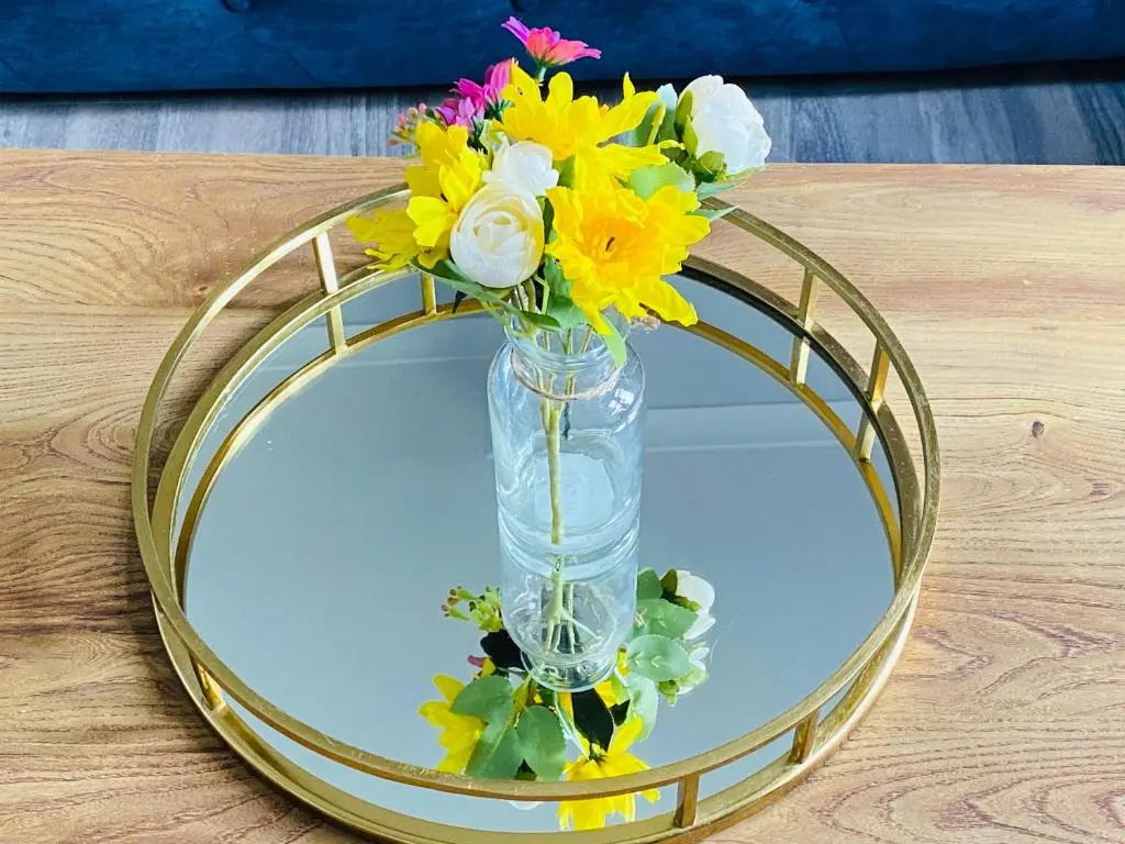 a vase filled with flowers sitting on a round mirror at Castle Grant Apartment in Inverness