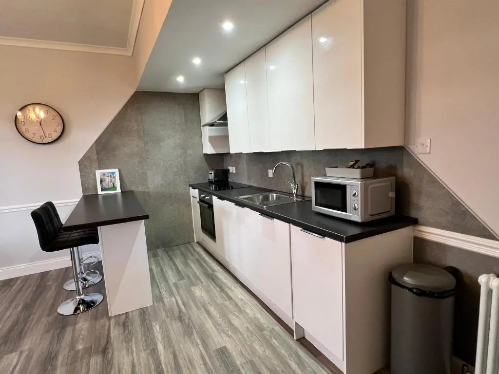 a kitchen with white cabinets and a sink and a microwave at Castle Grant Apartment in Inverness