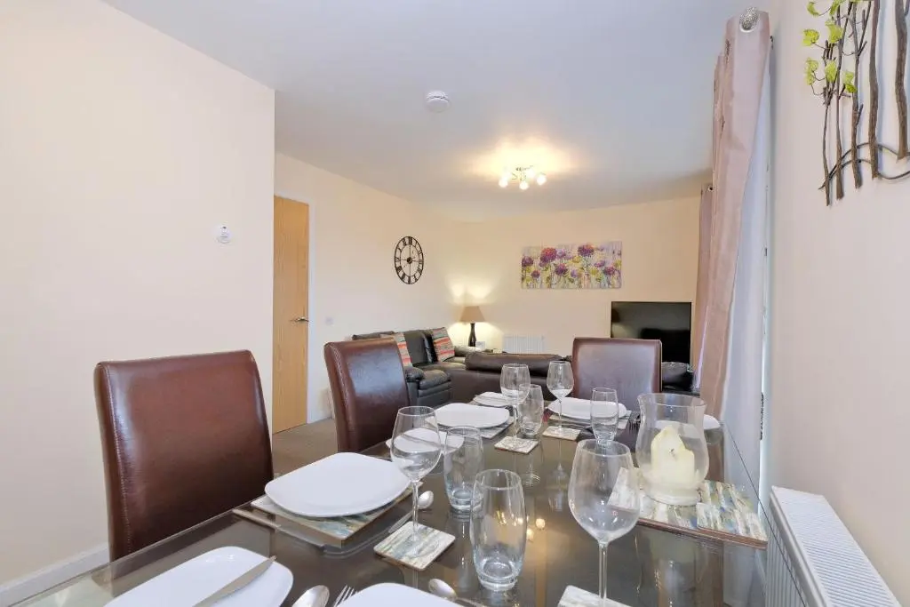 a dining room with a table with wine glasses on it at Caledonia Newhills Apartment in Aberdeen
