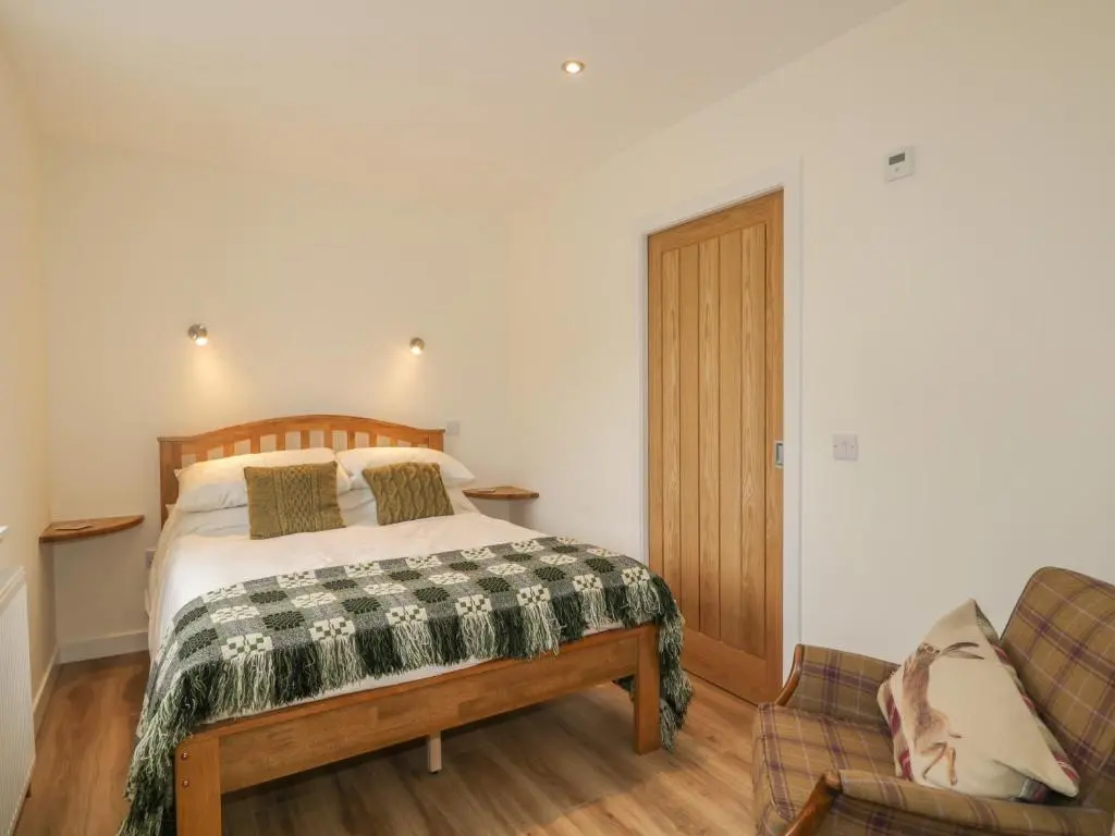 a bedroom with a bed and a couch at Enzie Station Cottage in Buckie