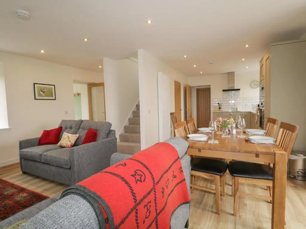 a living room with a table and a dining room at Enzie Station Cottage in Buckie