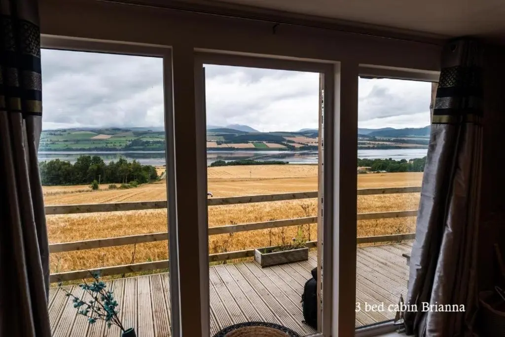 a room with a window with a view of the water at Culbokie Lodges in Culbokie