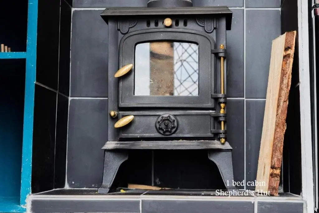 a black stove with a window on a wall at Culbokie Lodges in Culbokie