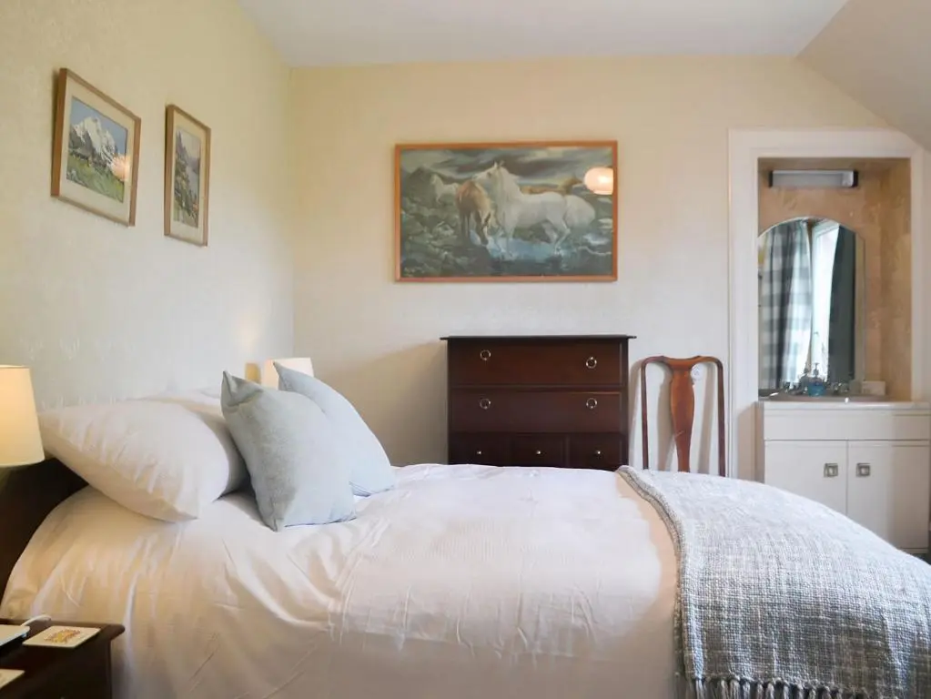 a bedroom with a bed and a painting of horses at Braehead in Nairn