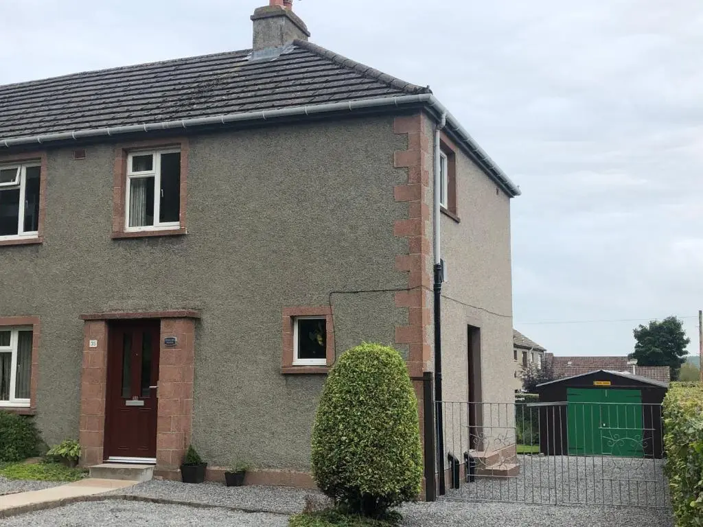 a grey brick house with a green door at Dallaire House in Banchory