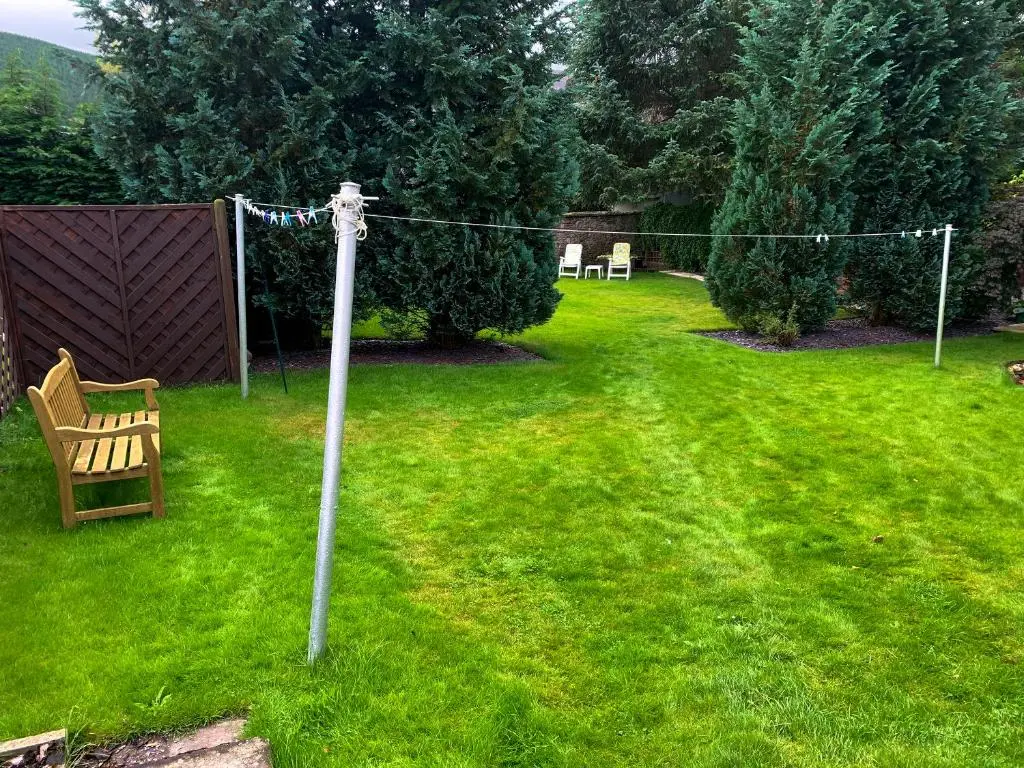 a yard with a chair and a clothesline in the grass at The Coyles - Uk31466 in Ballater