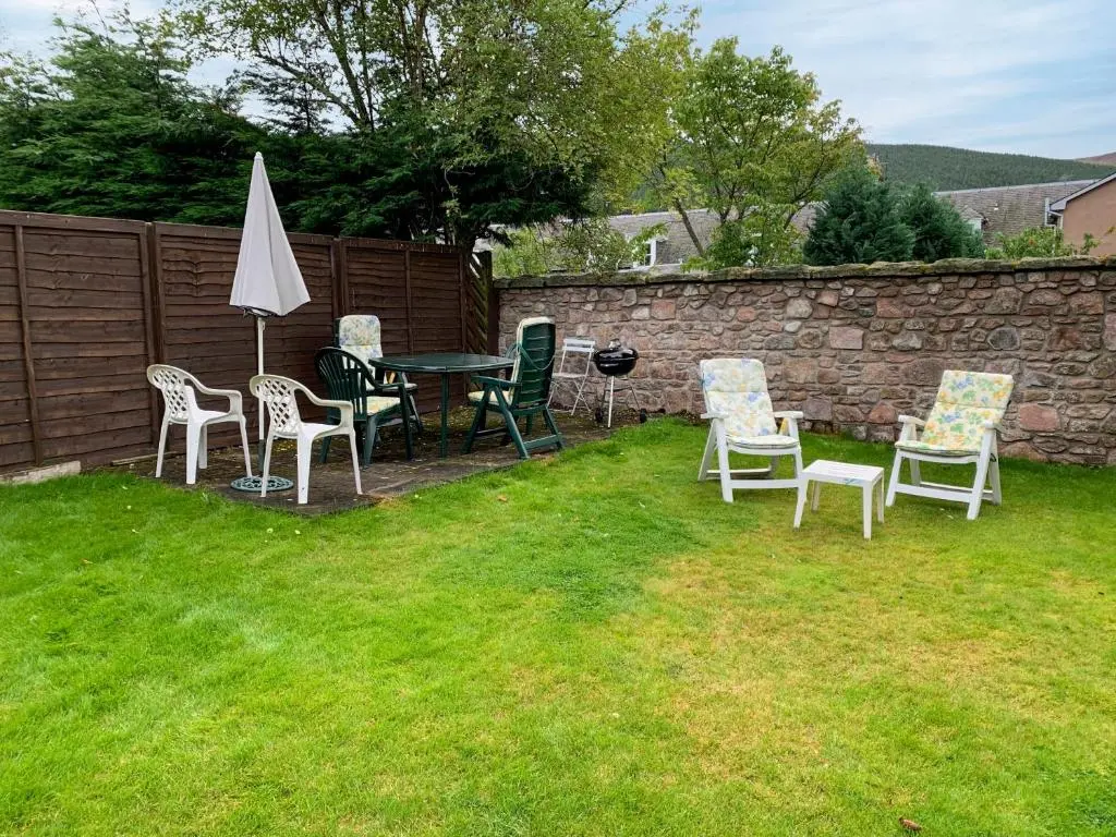 a patio with chairs and a table and an umbrella at The Coyles - Uk31466 in Ballater
