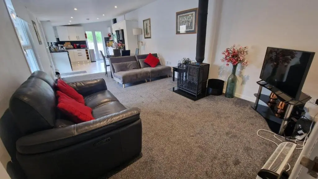a living room with a leather couch and a television at Spacious well equipped Chalet Bungalow close to Nairn, in Auldearn